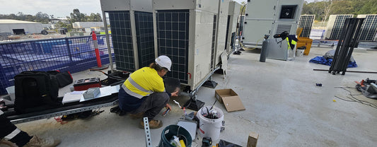Technician commissioning rooftop air conditioning condensers and air handling plant at a Brisbane commercial site