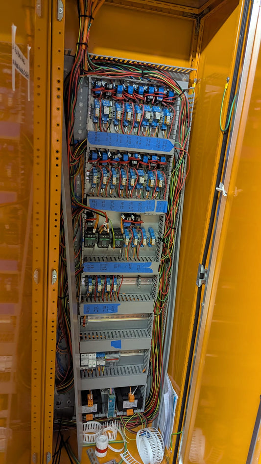 Interior of a commercial switchboard showing control relays, timers and terminal blocks on DIN rail